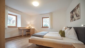 Un dormitorio con una cama, un escritorio y dos ventanas.