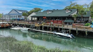 Eine Uferpromenade mit Booten, ein Gebäude mit der Aufschrift 'The Law House' und ein Restaurant namens 'Dead Duck Saloon'.