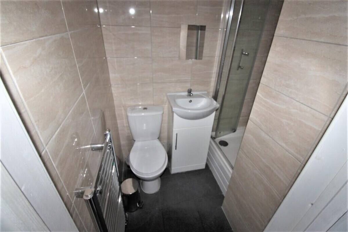 A compact bathroom with a toilet, sink, and shower.