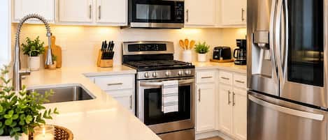 A modern kitchen with white cabinets, stainless steel appliances, and a central island with a sink.
