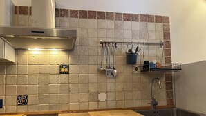 Una cocina con campana de acero inoxidable, encimera de madera, pileta y salpicadero de azulejos.