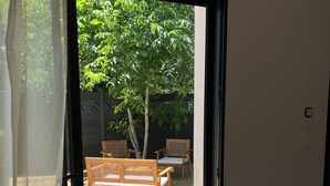 A room with a sliding glass door leading to an outdoor deck with wooden furniture. - The River's Cocoon (Saint-Drézéry)