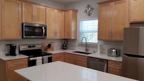 A modern kitchen with wooden cabinets, stainless steel appliances, and a central island. - Charming 3-bedroom house in marvelous Dallas with AC comfort (Dallas)