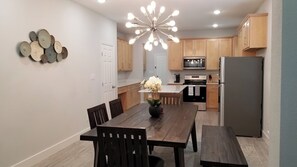 A modern kitchen with wooden cabinets, a stainless steel refrigerator, and a dining area with a wooden table and chairs. - Charming 3-bedroom house in marvelous Dallas with AC comfort (Dallas)