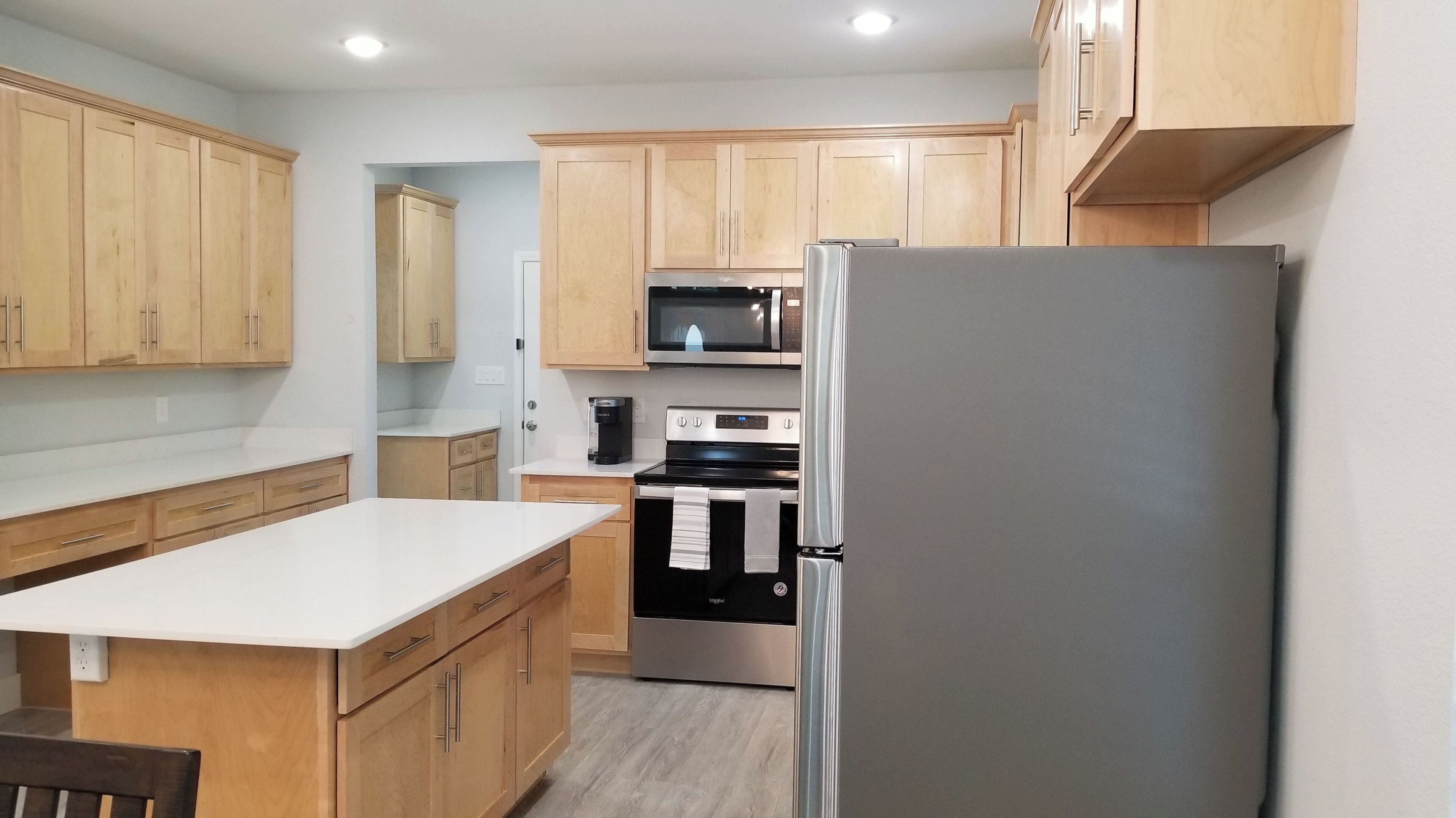 A compact kitchen with wooden cabinets, a stainless steel refrigerator, a microwave, and an oven.