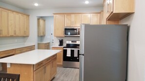 A compact kitchen with wooden cabinets, a stainless steel refrigerator, a microwave, and an oven.