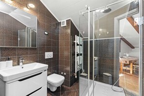Ein modernes Badezimmer mit einer Duschkabine aus Glas, einem weißen Waschbecken und einer Toilette.