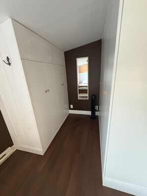 Une pièce avec une grande armoire blanche, un miroir au mur et un plancher marron.