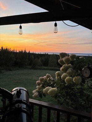 A deck with a telescope, hanging light fixtures, and a clock.