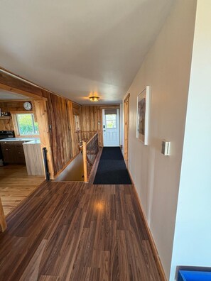 A hallway with wooden walls and a carpeted floor leading to a door.