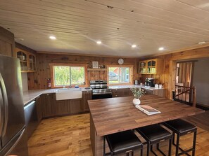 Eine moderne Küche mit Holzschränken, einem Edelstahlkühlschrank und einer großen Kücheninsel mit Barhocker.