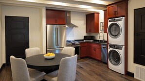 A modern kitchen with stainless steel appliances, a dining table with chairs, and a large window.