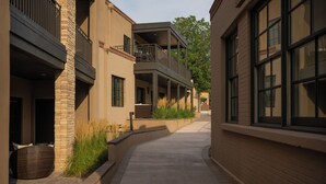 A corridor with a covered outdoor seating area, a brick wall, and a window on the right.