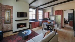 A modern kitchen with a built-in stove, a dining area with a round table, and a living room with a fireplace.