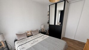 Een slaapkamer met een bed, nachtkastjes, een kledingkast en een nachttafel.
