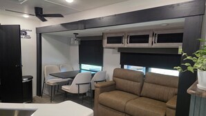 A compact RV interior with a dining area, seating, a kitchenette, and a ceiling fan. - New RV Sleepy Owl ,2-bedroom, 2 bathroom, 1 mile from lake Somerville. (Somerville)