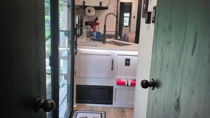 A narrow hallway leading to a kitchen with a sink, a window, and a door. - New RV Sleepy Owl ,2-bedroom, 2 bathroom, 1 mile from lake Somerville. (Somerville)