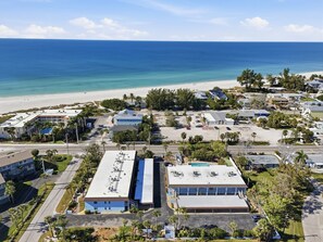 An aerial view of a coastal residential area with buildings, a beach, and a clear sky. - Recently Renovated 2bd/2ba a block from the beach & steps from the pool on AMI (Holmes Beach)