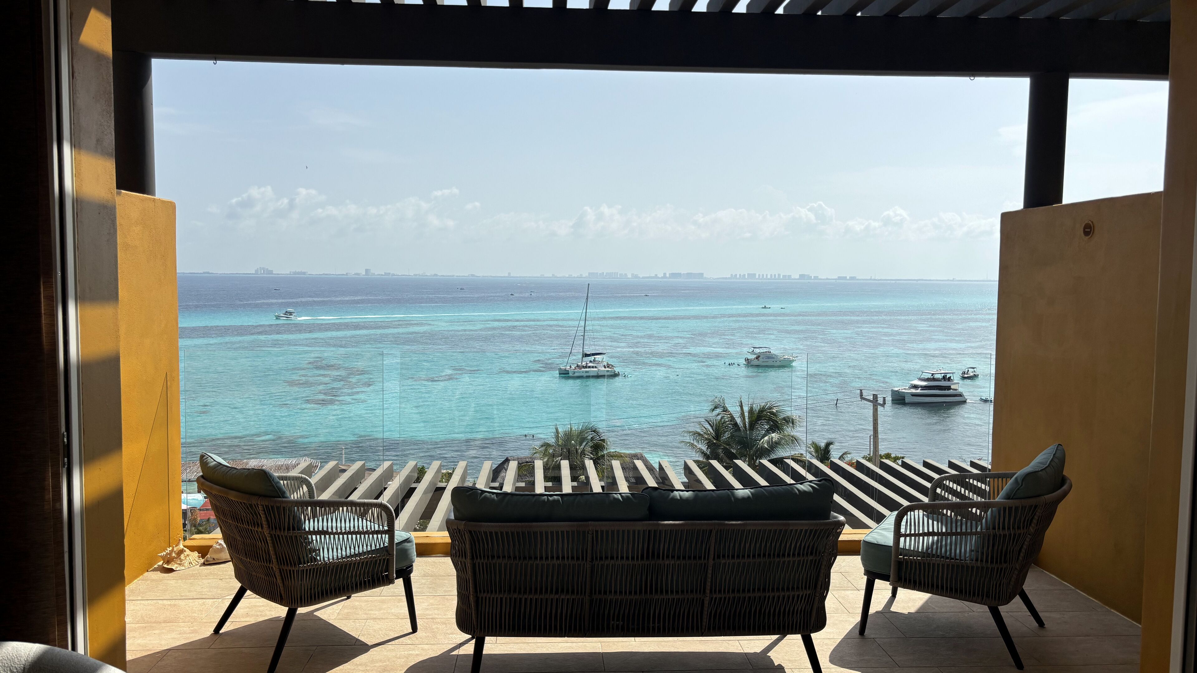 A balcony with wicker furniture overlooking a marina with boats.