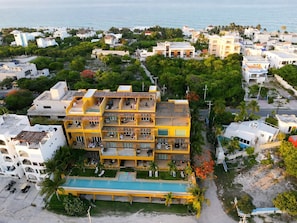 A multi-story hotel with balconies, a swimming pool, and a view of the sea. - Oceanview 3-Level Penthouse with Rooftop Terrace and Pool (Isla Mujeres)