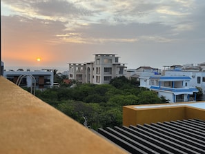 A residential area with modern buildings, a clear sky, and a sunset. - Oceanview 3-Level Penthouse with Rooftop Terrace and Pool (Isla Mujeres)