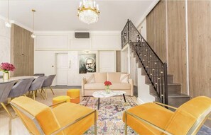 Ein modernes Wohnzimmer mit einer Couch, Sesseln, einem Couchtisch und einer Treppe.