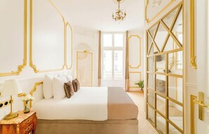 Ein geräumiges Schlafzimmer mit einem großen Bett, einem Nachttisch, einer Chandelier und Blick durch eine Glastür.