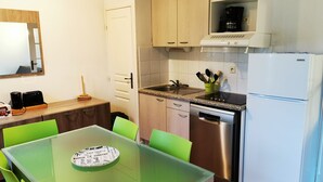 Eine kompakte Küche mit Geschirrspüler, Kaffeemaschine und Kühlschrank.
