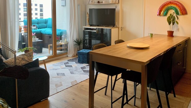 Een moderne woonruimte met een eethoek, een televisie en een schuifdeur naar een terras.