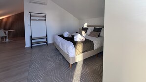 Une chambre d’hôtel moderne, équipée d’un lit, d’un bureau, d’une chaise, d’un fauteuil suspendu et d’un tapis à motifs.