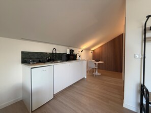Eine moderne Küche mit Geschirrspüler, Mikrowelle und Kaffeemaschine. Ein Essbereich mit Tisch und Stühlen ist ebenfalls vorhanden.