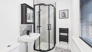 A bathroom with a shower, toilet, sink, and a patterned floor.