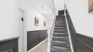 A staircase with a handrail, a door with a keypad, and framed artwork on the walls.
