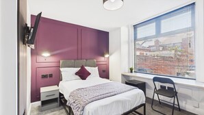 A bedroom with a bed, bedside tables, a desk, and a chair.