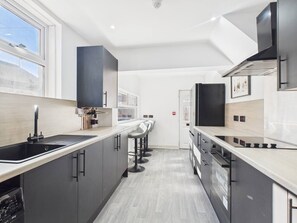A modern kitchen with a long countertop, black cabinets, and a window providing natural light.