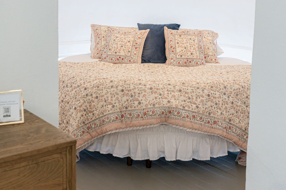 A bedroom with a bed, a dresser, and a white ceiling.