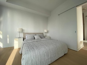 A bedroom with a bed, two bedside tables, and a door. - Maple Square Hotel (Toronto)