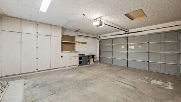Een garage met meerdere opbergkasten, een werkbank en een betonnen vloer.