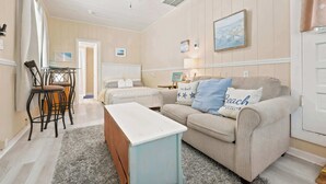 Una habitación con cama, sofá, mesa y ventilador de techo.