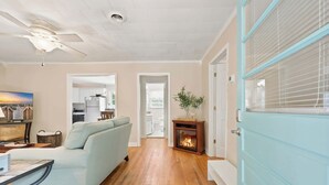 Una sala de estar con sofá, chimenea, mesa de comedor y cocina al fondo.