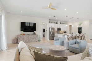 A modern living room with a flat-screen TV, sofas, a coffee table, and a dining area with chairs. - Coastal Retreat with Private Pool - Minutes from 30A Beaches (Santa Rosa Beach)