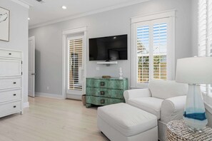 A living room with a white sofa, a teal chest of drawers, a flat-screen TV, and a lamp on a side table. - Coastal Retreat with Private Pool - Minutes from 30A Beaches (Santa Rosa Beach)