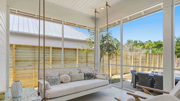 A covered outdoor seating area with a swing, a table, and chairs. - Coastal Retreat with Private Pool - Minutes from 30A Beaches (Santa Rosa Beach)