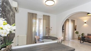 Uma sala de estar moderna com área de jantar, um sofá, uma mesa de centro e um vaso com planta.