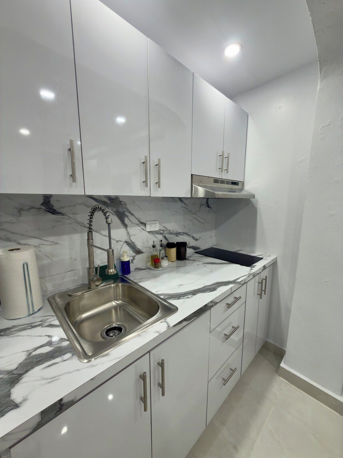 Een moderne keuken met witte kasten, een marmeren aanrechtblad en een roestvrijstalen spoelbak.