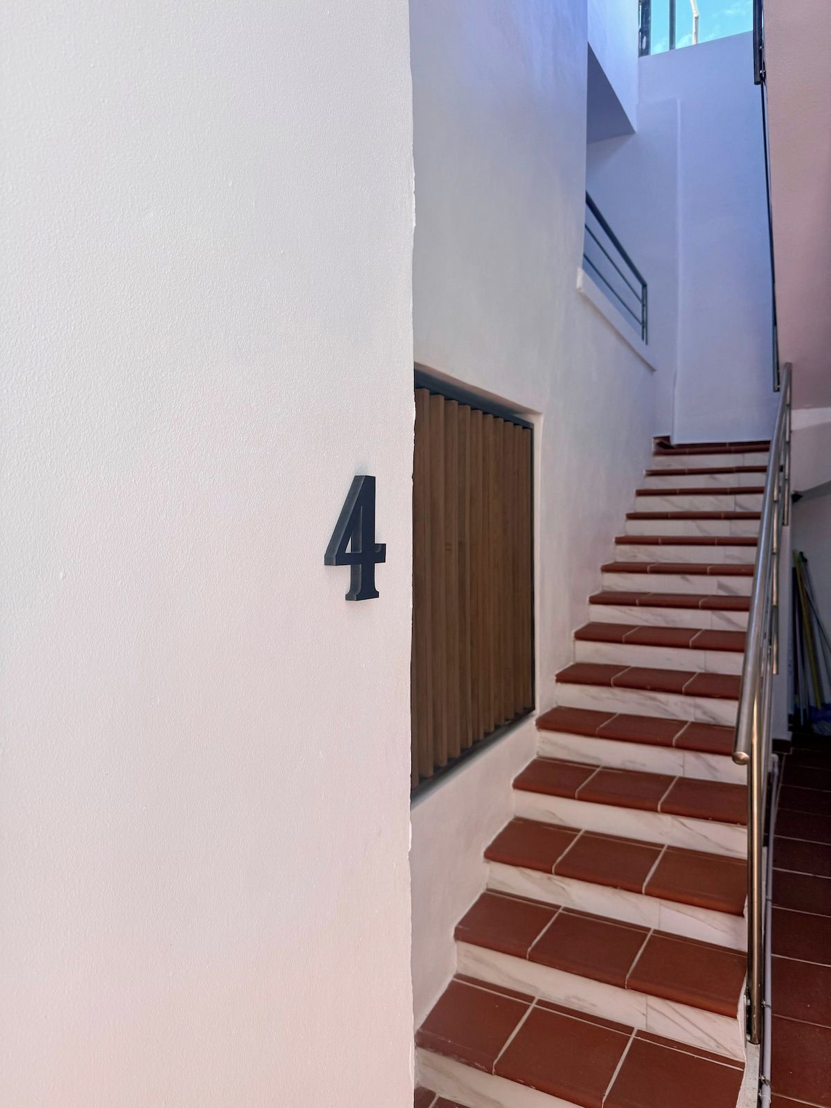 Un escalier avec une rampe, une porte en bois et un mur portant le chiffre « 4 », qui indique le numéro de l’étage.