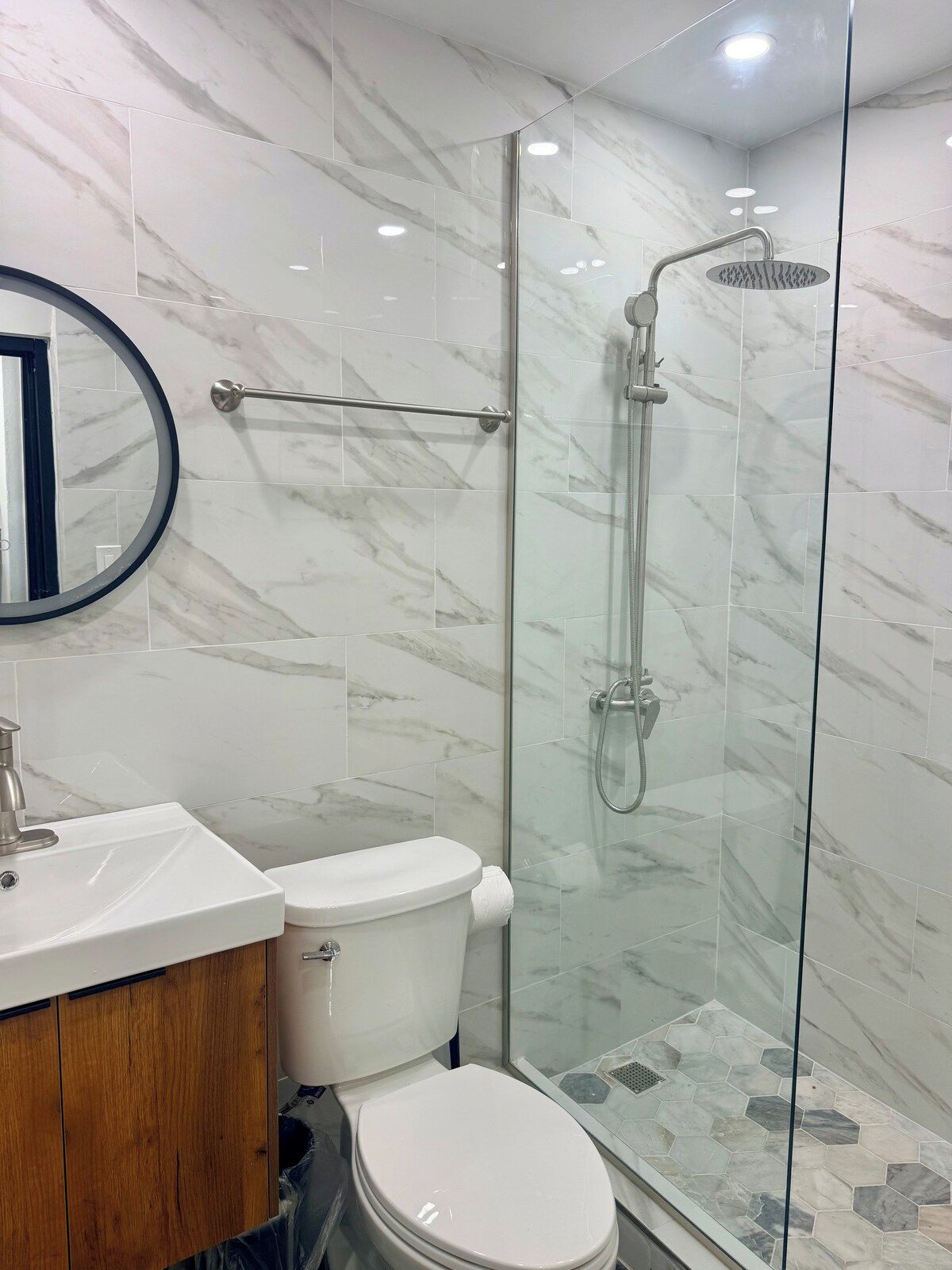 Un baño moderno con cabina de ducha de vidrio, inodoro y lavamanos.