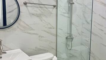 Un baño moderno con cabina de ducha de vidrio, inodoro y lavamanos.