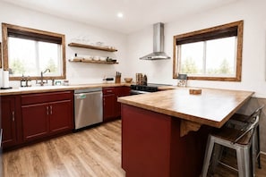 Une cuisine moderne avec des plans de travail en bois, des armoires rouges et un lave-vaisselle encastré.