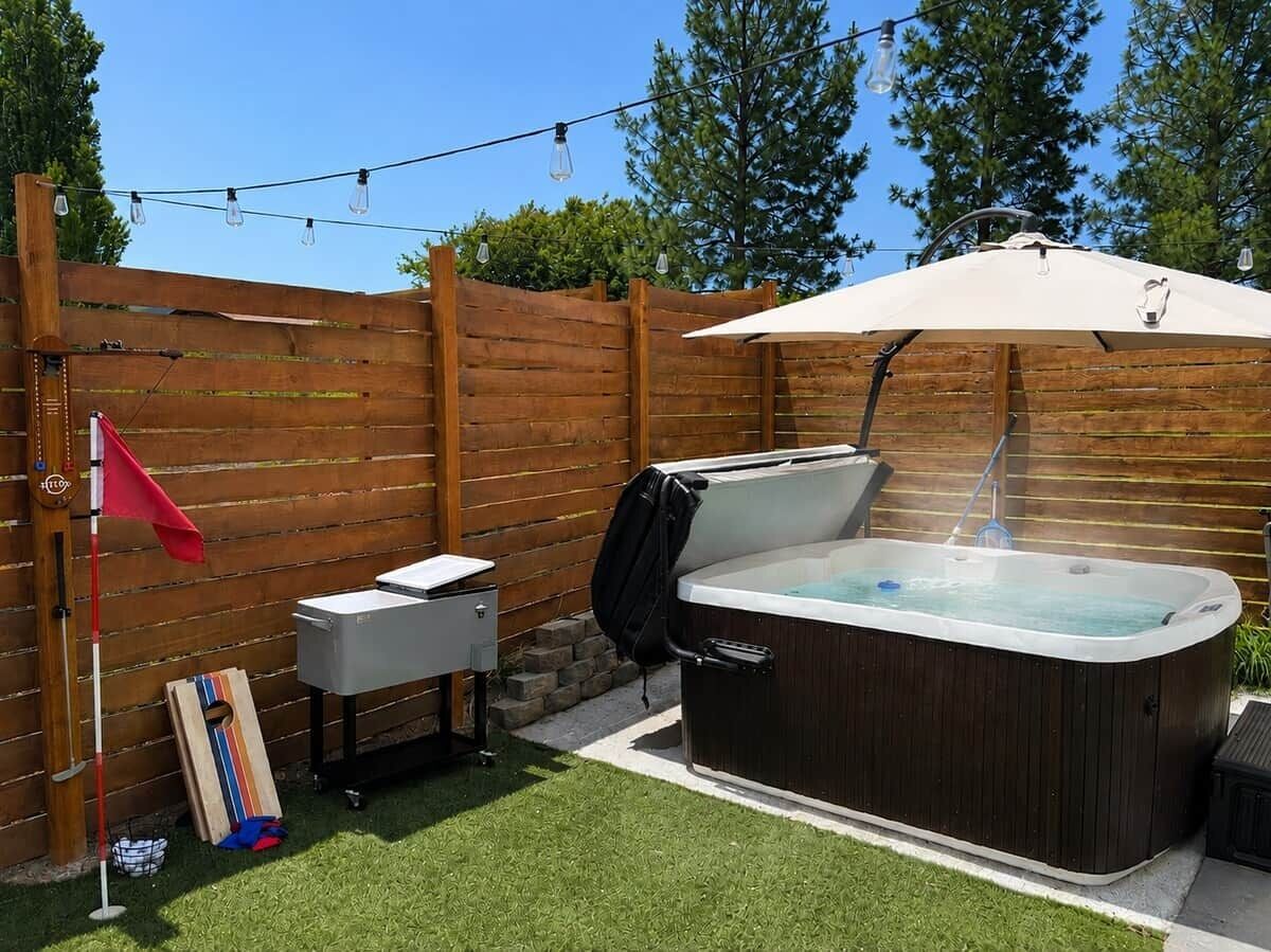 A hot tub with a canopy, a wooden fence, and a small table with a flag.